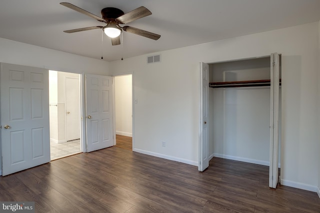 unfurnished bedroom featuring baseboards, visible vents, ceiling fan, dark wood-style flooring, and a closet