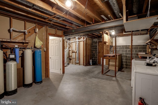 unfinished below grade area featuring concrete block wall and separate washer and dryer