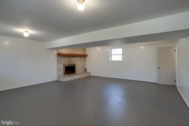 unfurnished living room featuring a brick fireplace, finished concrete floors, and baseboards