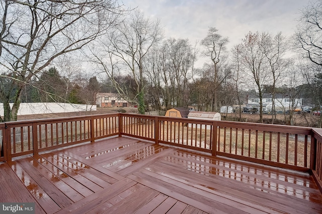 wooden terrace featuring a storage shed and an outbuilding