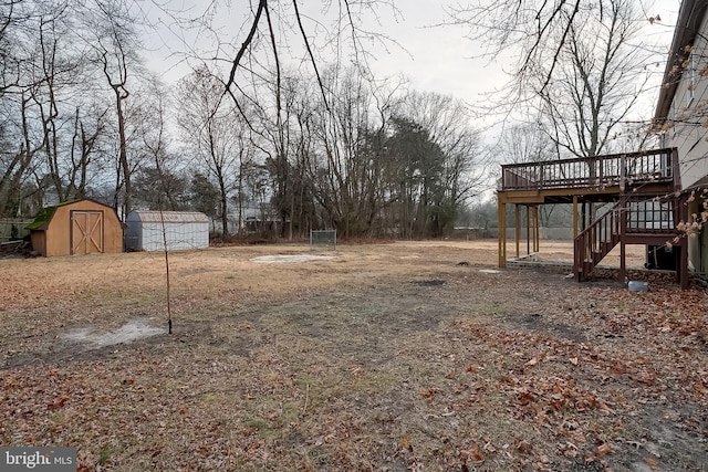 view of yard with stairs, an outdoor structure, a wooden deck, and a shed