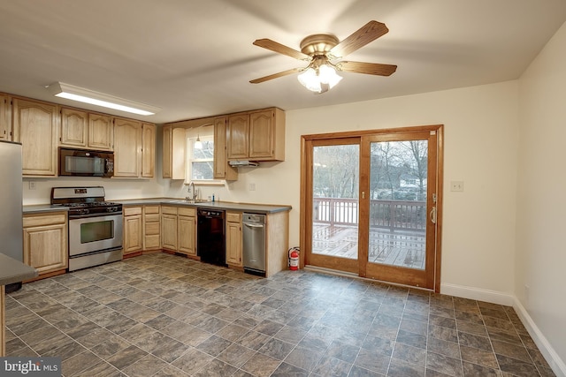 kitchen with stone finish floor, a sink, black appliances, ceiling fan, and baseboards