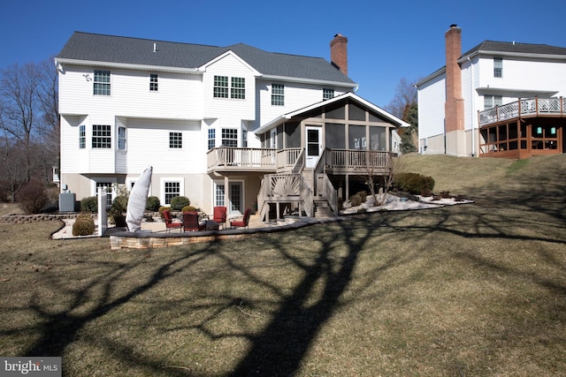 rear view of house featuring a patio, cooling unit, a sunroom, a lawn, and a chimney