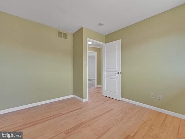 empty room featuring visible vents, light wood-style flooring, and baseboards