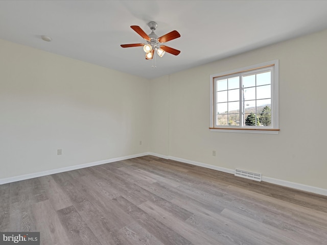 unfurnished room featuring ceiling fan, visible vents, baseboards, and wood finished floors