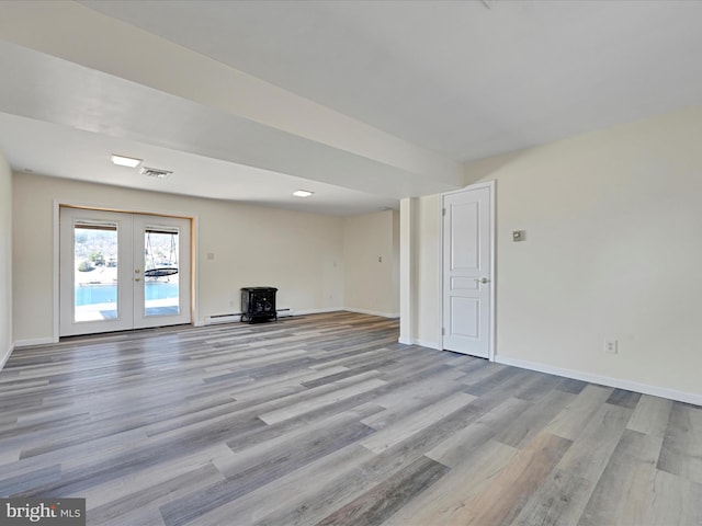 unfurnished living room with wood finished floors, visible vents, and baseboards