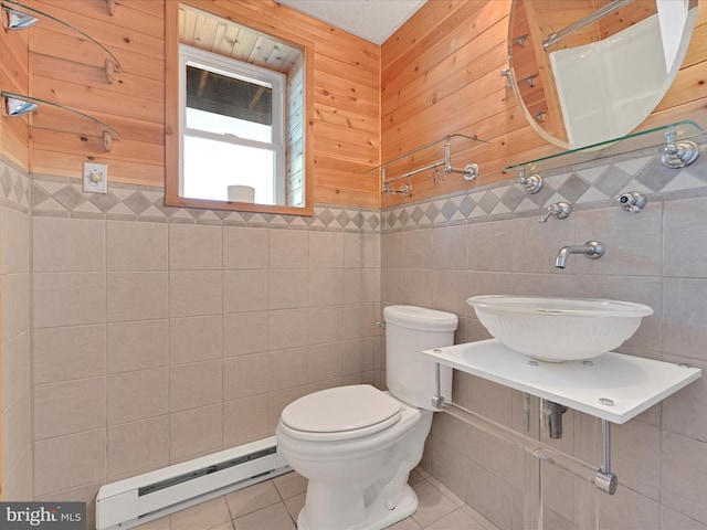 bathroom featuring tile patterned floors, toilet, a sink, tile walls, and a baseboard radiator