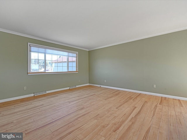 spare room with light wood-style floors, visible vents, and ornamental molding