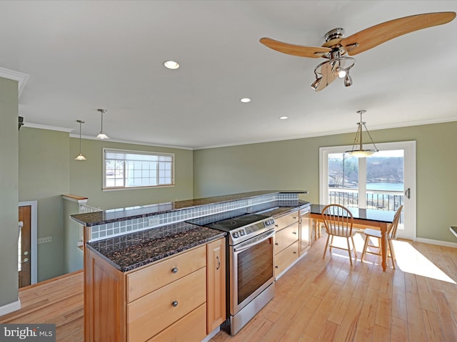 kitchen with stainless steel electric range oven, a wealth of natural light, light brown cabinets, and light wood finished floors