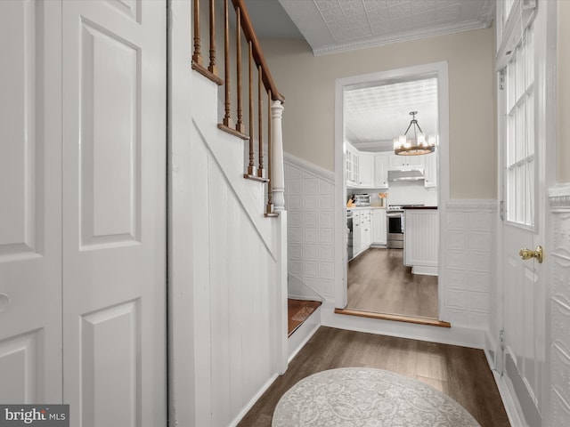 entryway with a wainscoted wall, a notable chandelier, stairway, and dark wood-style flooring