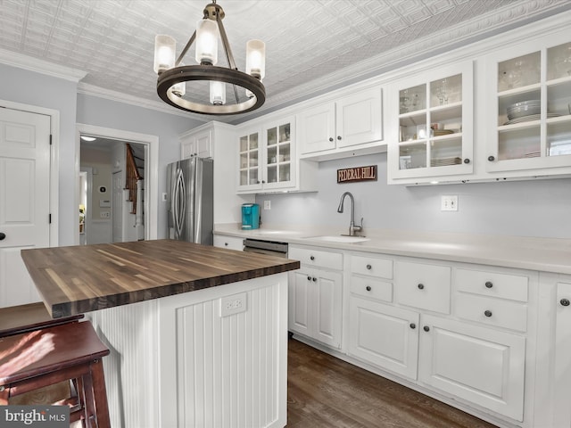 kitchen with butcher block counters, an ornate ceiling, crown molding, stainless steel refrigerator with ice dispenser, and a sink