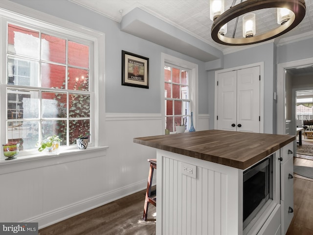 kitchen featuring ornamental molding, stainless steel microwave, dark wood finished floors, and wood counters