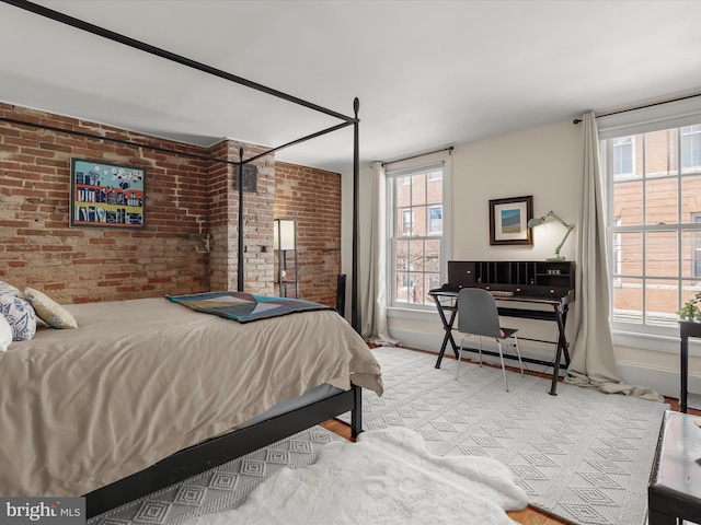 bedroom with brick wall, multiple windows, and baseboards