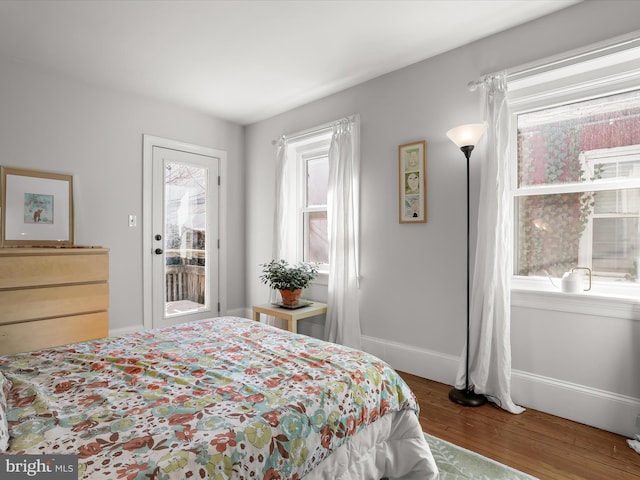 bedroom with access to exterior, baseboards, and wood finished floors