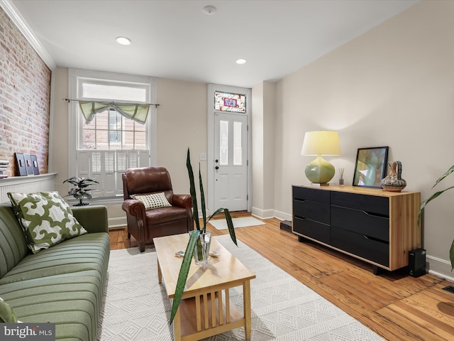 living room with recessed lighting, brick wall, light wood-style flooring, and baseboards