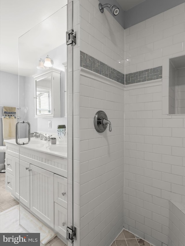 full bathroom with tile patterned flooring, tiled shower, and vanity