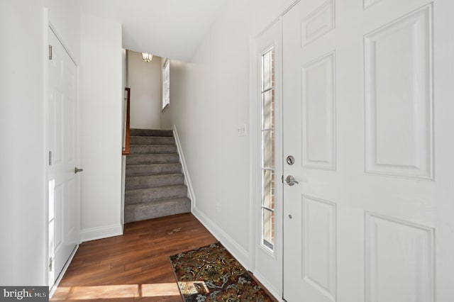 entrance foyer with stairs, dark wood finished floors, and baseboards