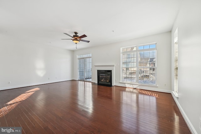 unfurnished living room with ceiling fan, dark wood-style flooring, a fireplace with flush hearth, and baseboards