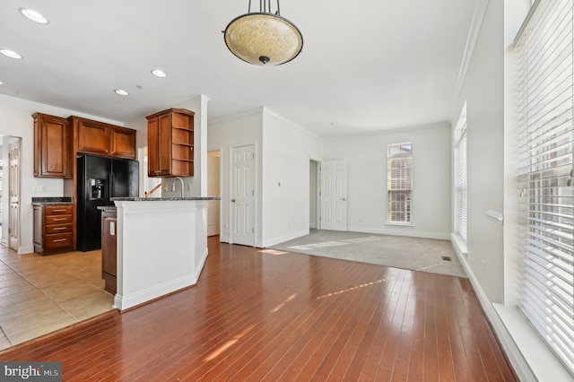 kitchen with pendant lighting, brown cabinetry, crown molding, and open floor plan