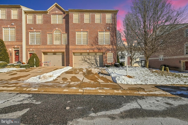 view of property with a garage, brick siding, and driveway