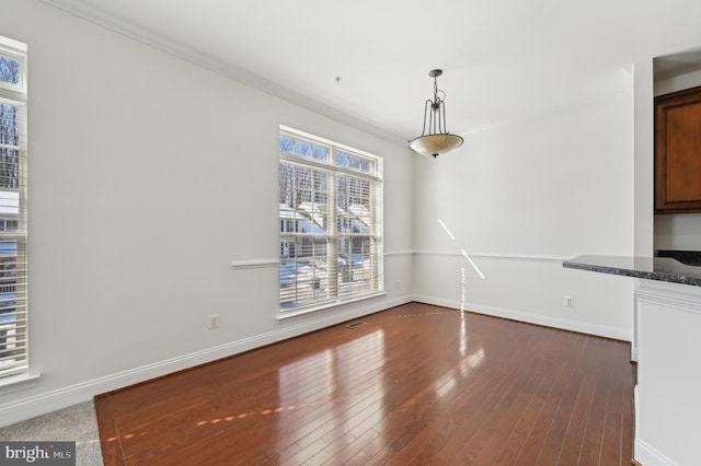 unfurnished dining area featuring baseboards, ornamental molding, and dark wood-style flooring