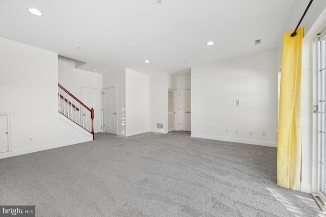 unfurnished living room with visible vents, baseboards, light colored carpet, stairs, and recessed lighting