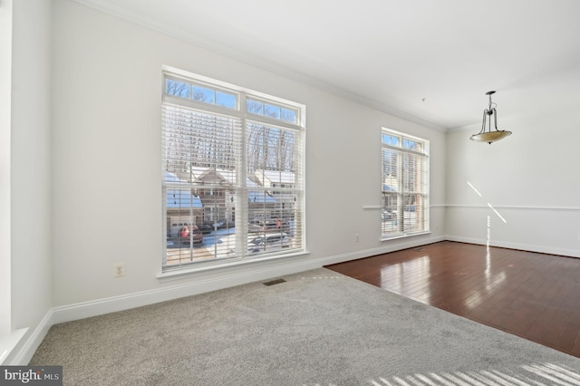 unfurnished dining area featuring crown molding, visible vents, carpet flooring, wood finished floors, and baseboards