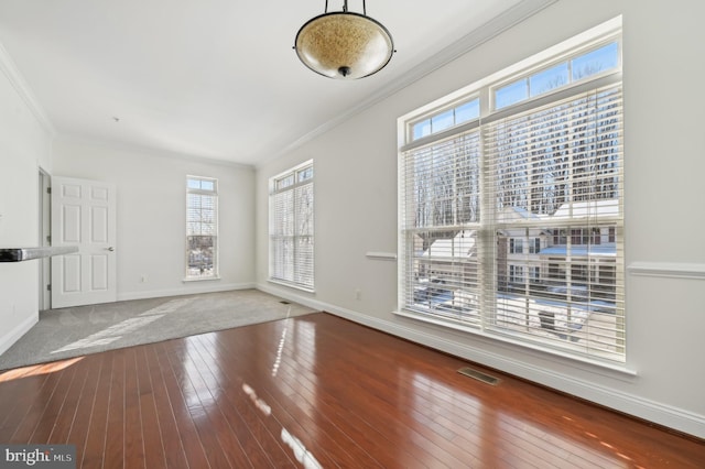 interior space featuring visible vents, crown molding, baseboards, and wood finished floors