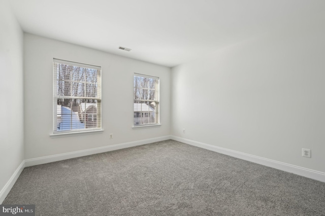 carpeted spare room with visible vents and baseboards