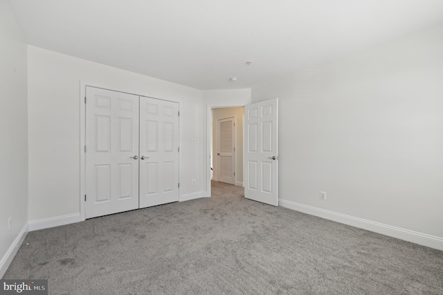 unfurnished bedroom with a closet, light carpet, and baseboards