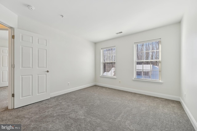 unfurnished room featuring carpet floors, visible vents, and baseboards