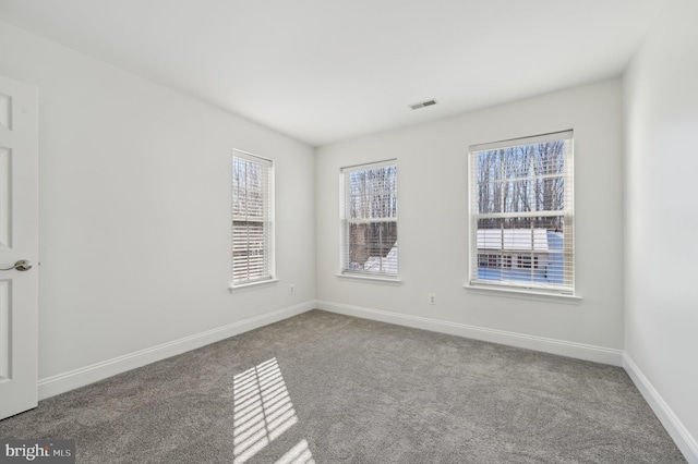 carpeted spare room featuring visible vents and baseboards