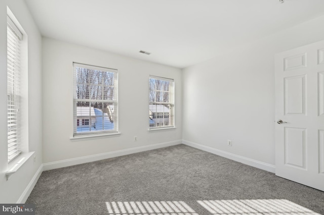 empty room with carpet floors, visible vents, and baseboards