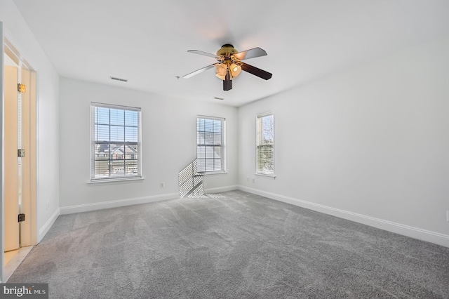 spare room featuring light colored carpet, ceiling fan, and baseboards