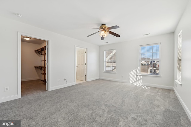 empty room with light colored carpet, ceiling fan, visible vents, and baseboards