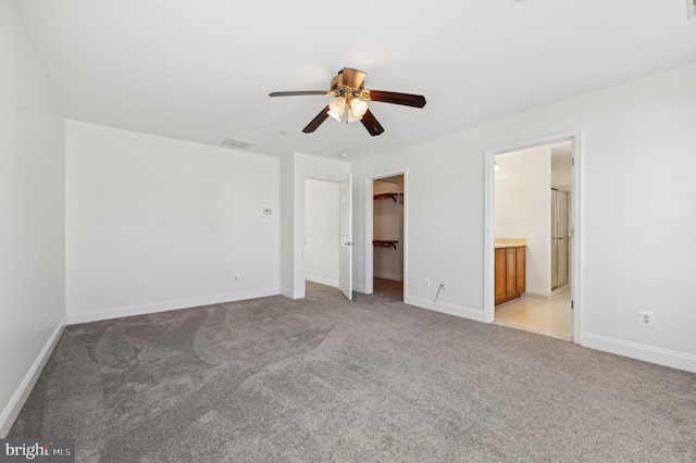 unfurnished bedroom with light carpet, a spacious closet, and baseboards