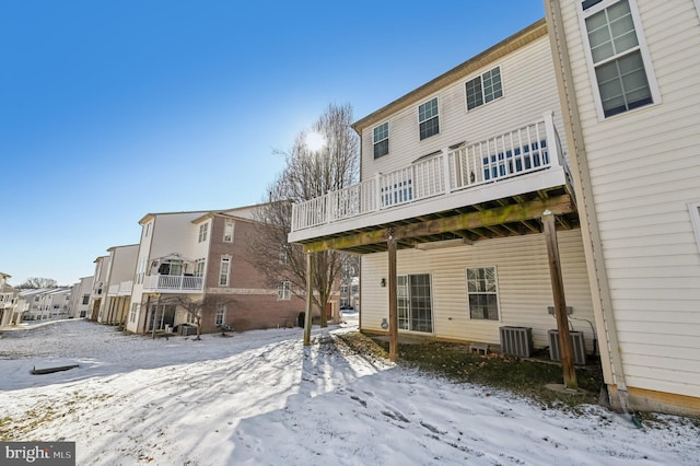 snow covered rear of property featuring central air condition unit