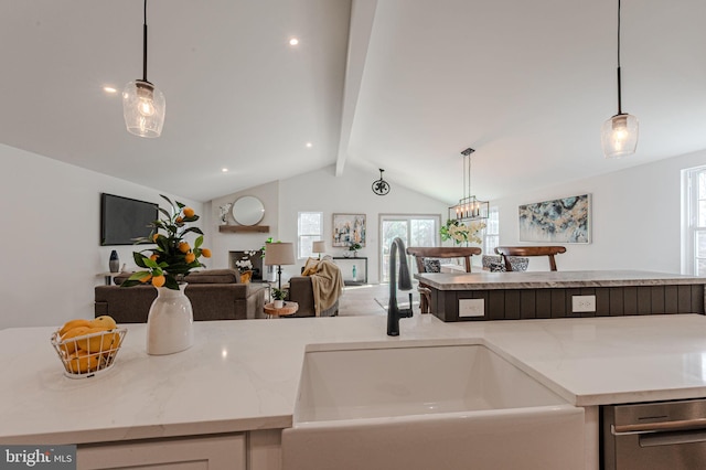 kitchen with lofted ceiling with beams, light stone counters, a sink, open floor plan, and hanging light fixtures