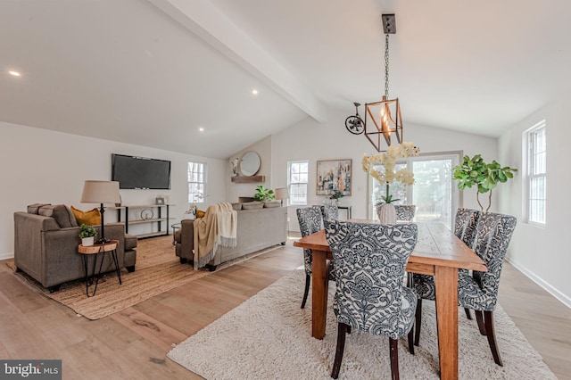 dining area with baseboards, a notable chandelier, lofted ceiling with beams, and light wood finished floors