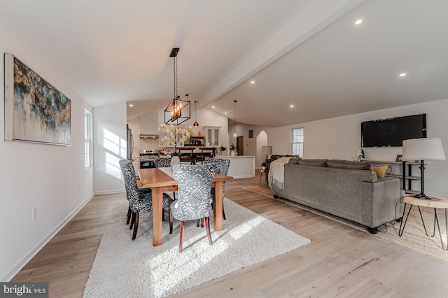 dining area with lofted ceiling with beams, arched walkways, a wealth of natural light, and light wood-style floors