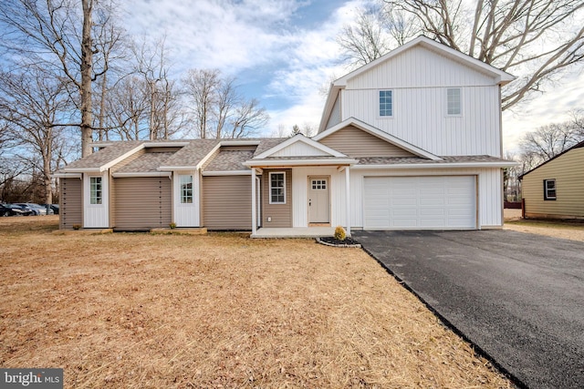 view of front facade with an attached garage, a shingled roof, and aphalt driveway