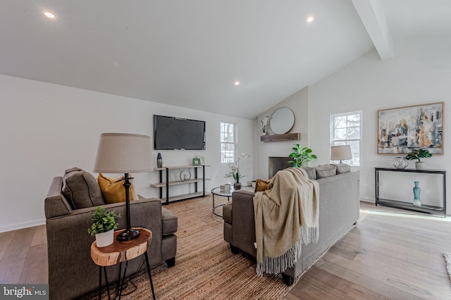 living room featuring lofted ceiling with beams, baseboards, and light wood-style floors