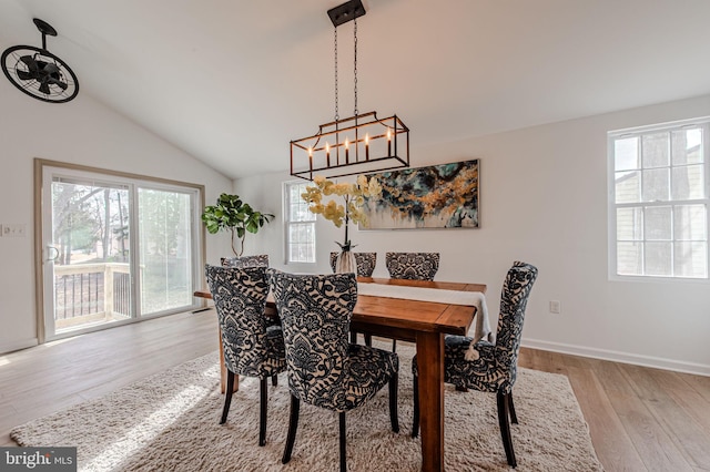 dining room featuring vaulted ceiling, light wood finished floors, and baseboards