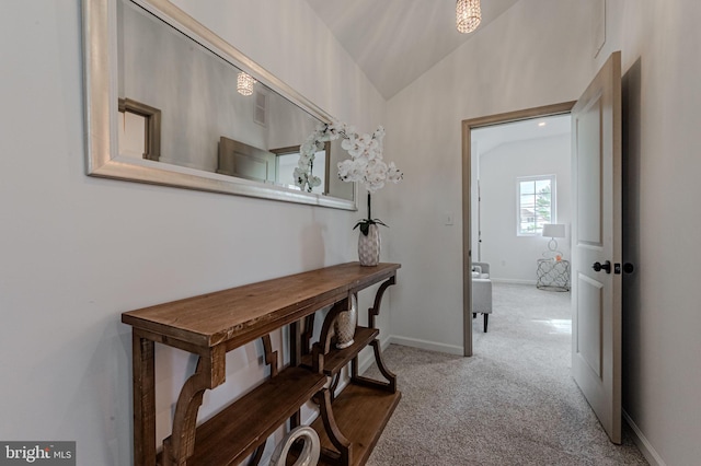 hallway with lofted ceiling, carpet flooring, and baseboards