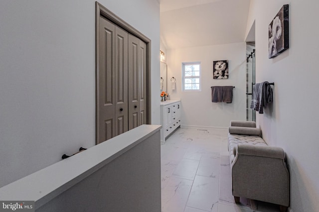 hall featuring marble finish floor, vaulted ceiling, and baseboards