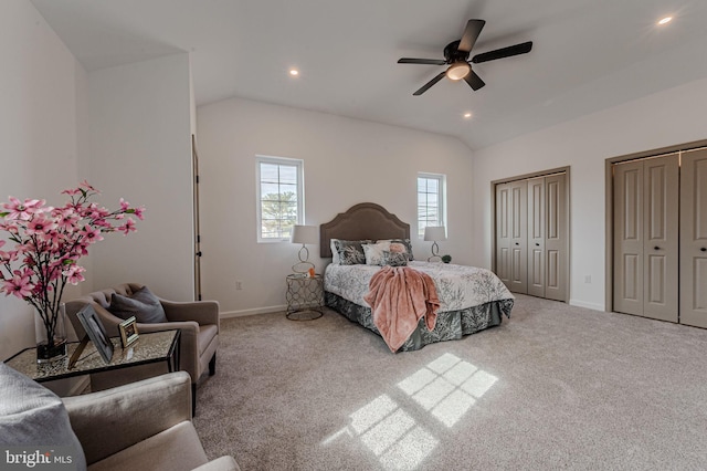 bedroom featuring lofted ceiling, carpet, baseboards, and two closets