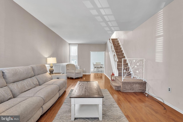 living room featuring stairs, wood finished floors, and baseboards