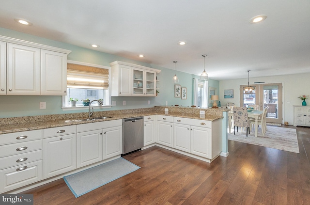 kitchen with dark wood-style floors, a peninsula, a sink, white cabinets, and dishwasher