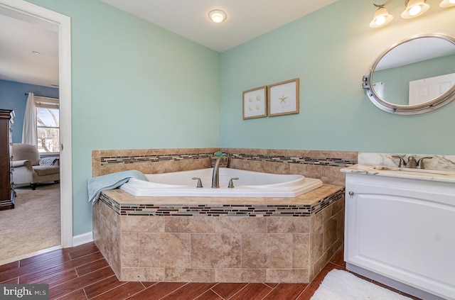 full bathroom featuring a bath, vanity, and wood finished floors