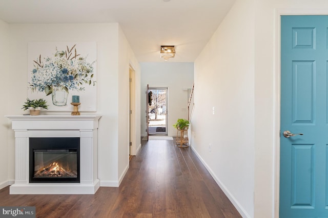 corridor with dark wood finished floors and baseboards